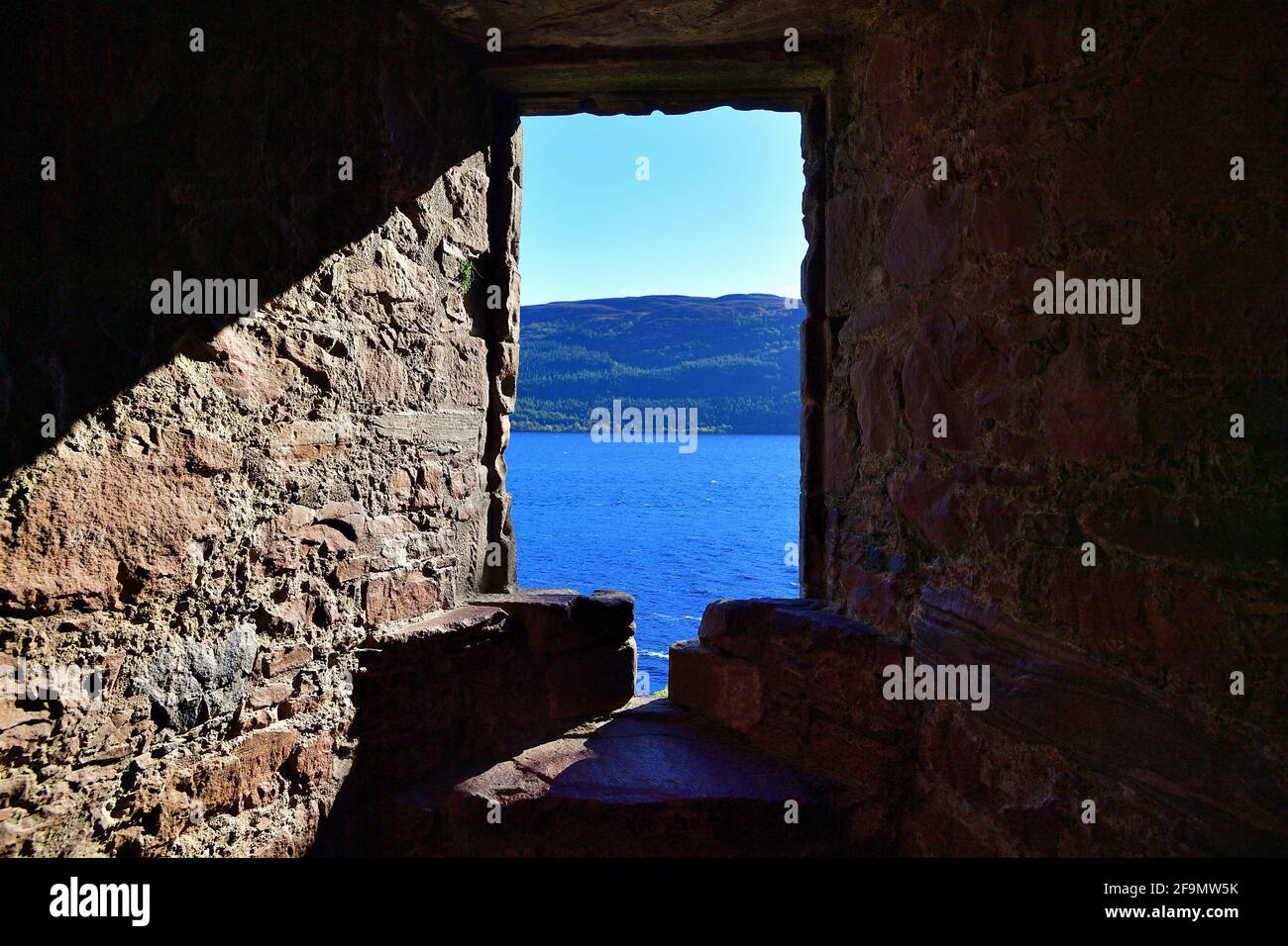 Drumnadrochit, Highland, Scozia, Regno Unito. Una vista attraverso una finestra al Castello Urquhart di Loch Ness e gli altopiani sulla riva opposta. Foto Stock