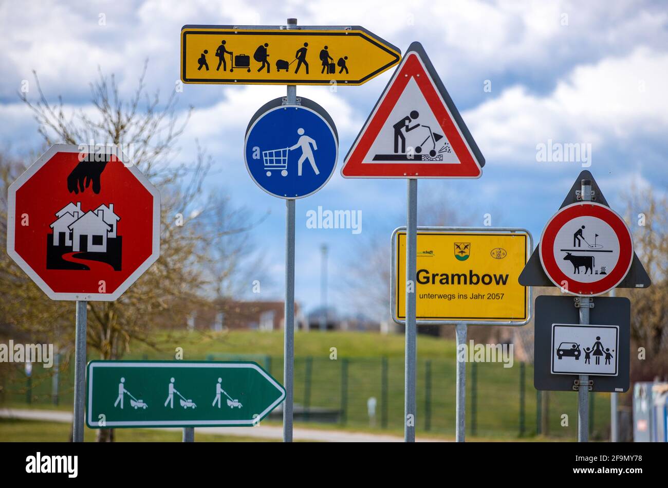 15 aprile 2021, Meclemburgo-Pomerania occidentale, Grambow: Segnali stradali del futuro stand come un progetto artistico del gruppo di artisti 'Reinigungsgesellschaft' (Martin Keil e Henrik Mayer) nel centro del paese. Gli artisti di Dresda hanno sviluppato un "sistema di guida per il nuovo Grambow 2057", che visualizza le idee e i suggerimenti per una migliore vita rurale in pittogrammi colorati. Il contenuto è il villaggio di Grambow nel 2057, quando il villaggio avrà 700 anni. Dodici segnali stradali in lamiera zincata si occupano di questioni come il cambiamento climatico, lo sviluppo demografico, l'occupazione, AN Foto Stock