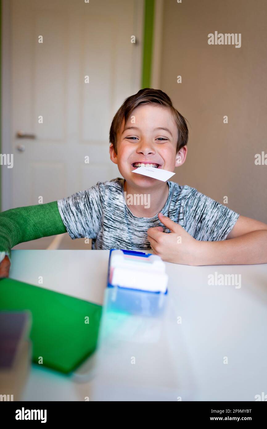 ragazzo freddo con il braccio verde si siede nella sua stanza e impara con le schede ed è felice Foto Stock