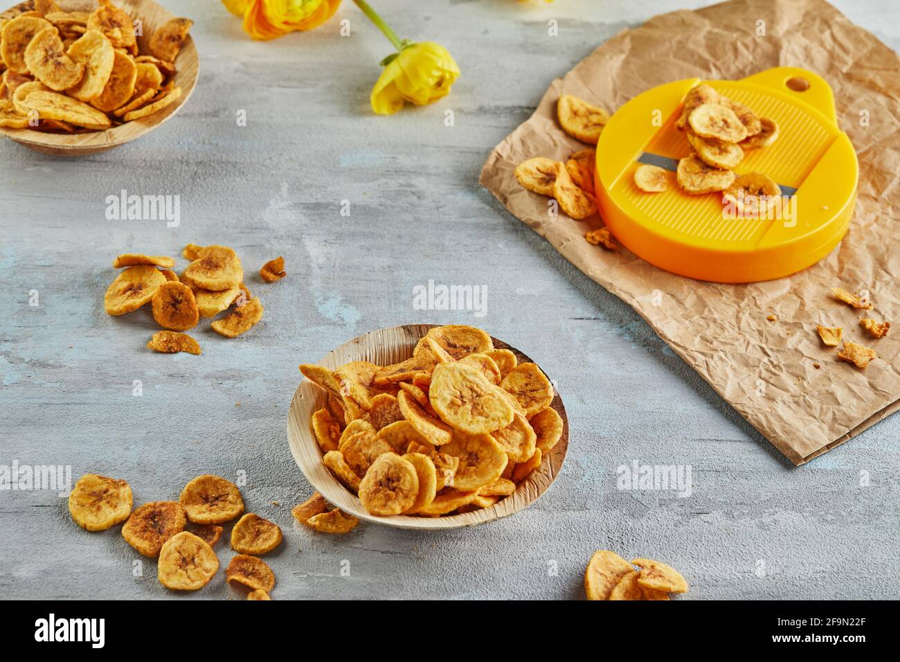 Banana chips cibo sano, frutta secca e patatine vegetali sane, sano snack vegan con taglierine. Foto Stock