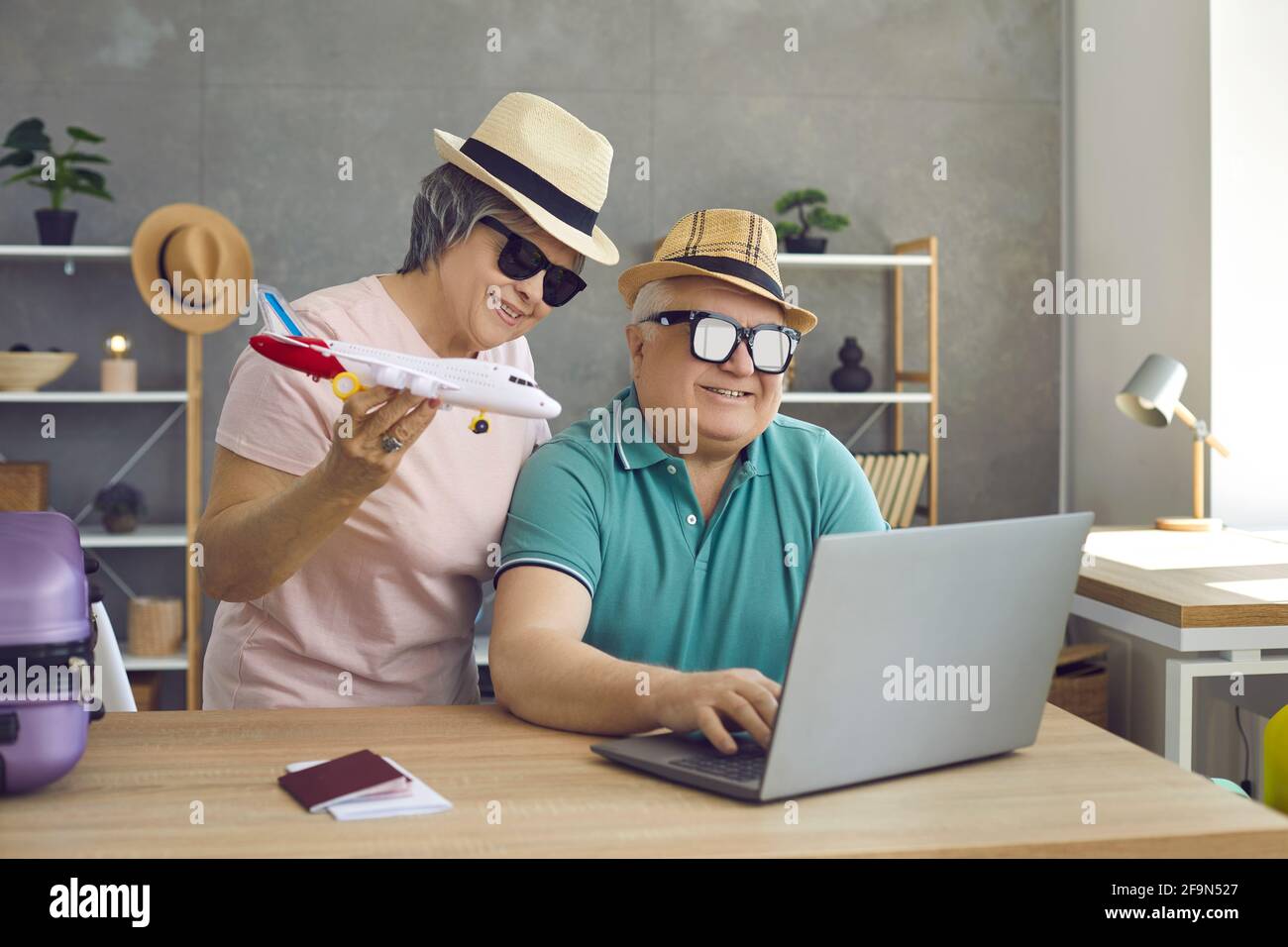 Divertente coppia anziana che pianifica una vacanza utilizzando un computer portatile per prenotare il tour volo Foto Stock