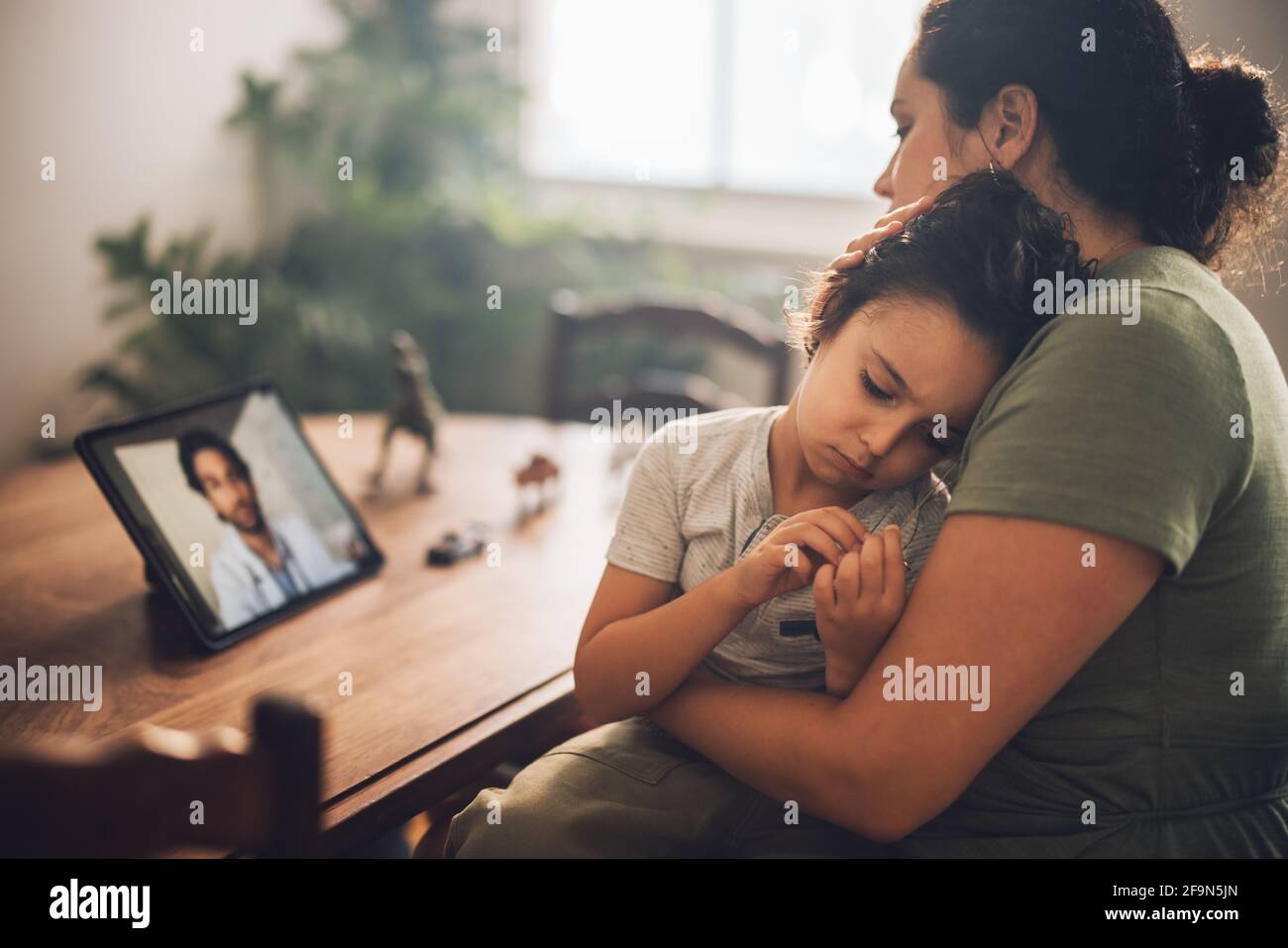 Madre con figlio che ha una videochiamata con un medico digitale a casa. Donna che si prende consiglio dal medico durante la telemedicina per il suo figlio malato. Foto Stock