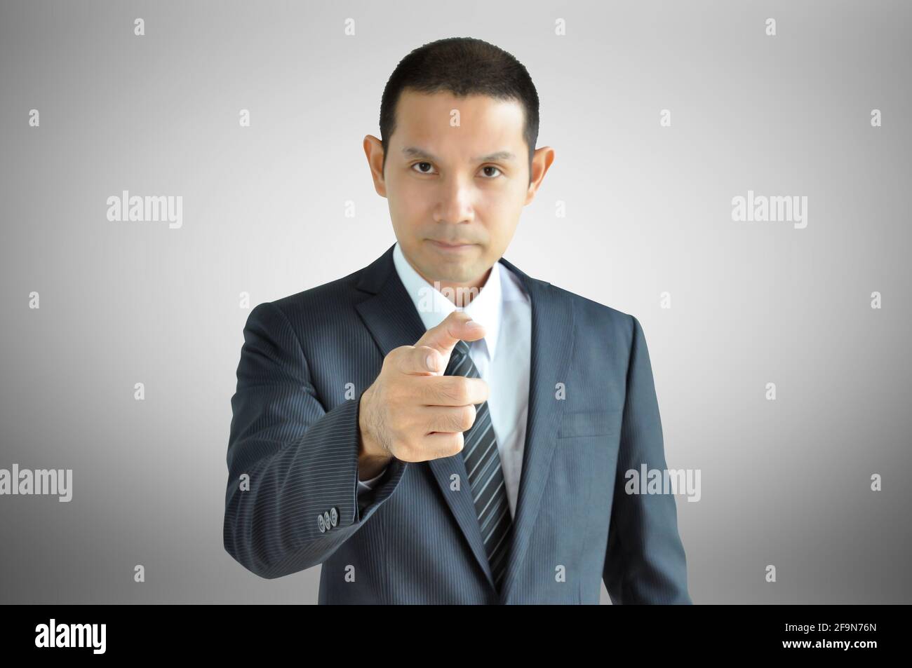 Uomo d'affari asiatico che punta il dito su di voi con il volto serio Foto Stock