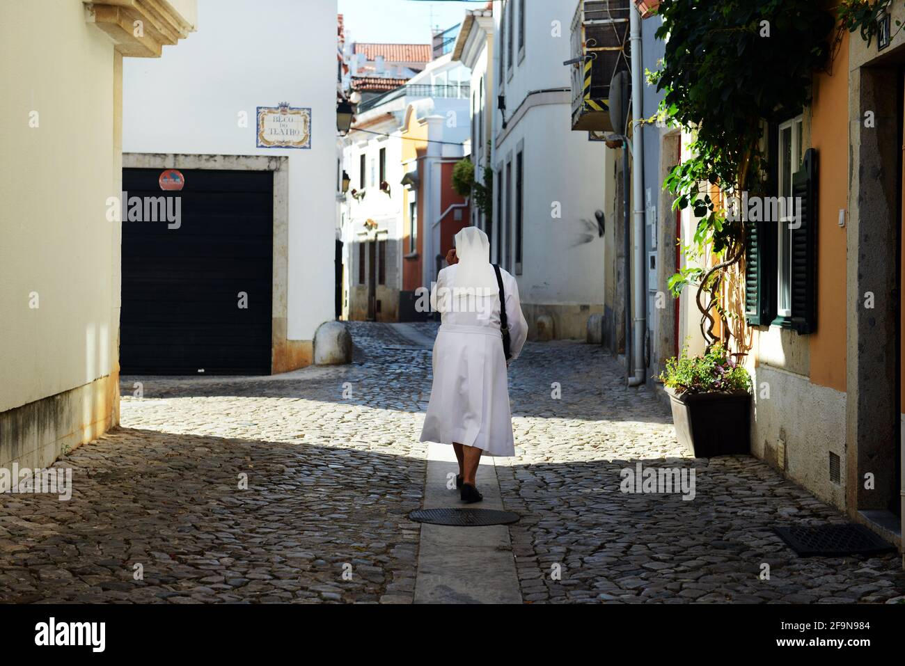 Una suora cattolica che cammina tra i vecchi edifici di Cascais, Portogallo. Foto Stock