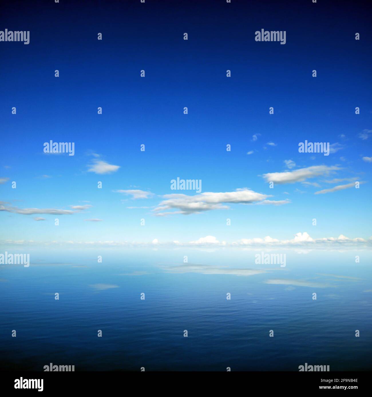 Cielo blu e nuvole con riflessione sull'acqua di mare - effetto bordo scuro Foto Stock