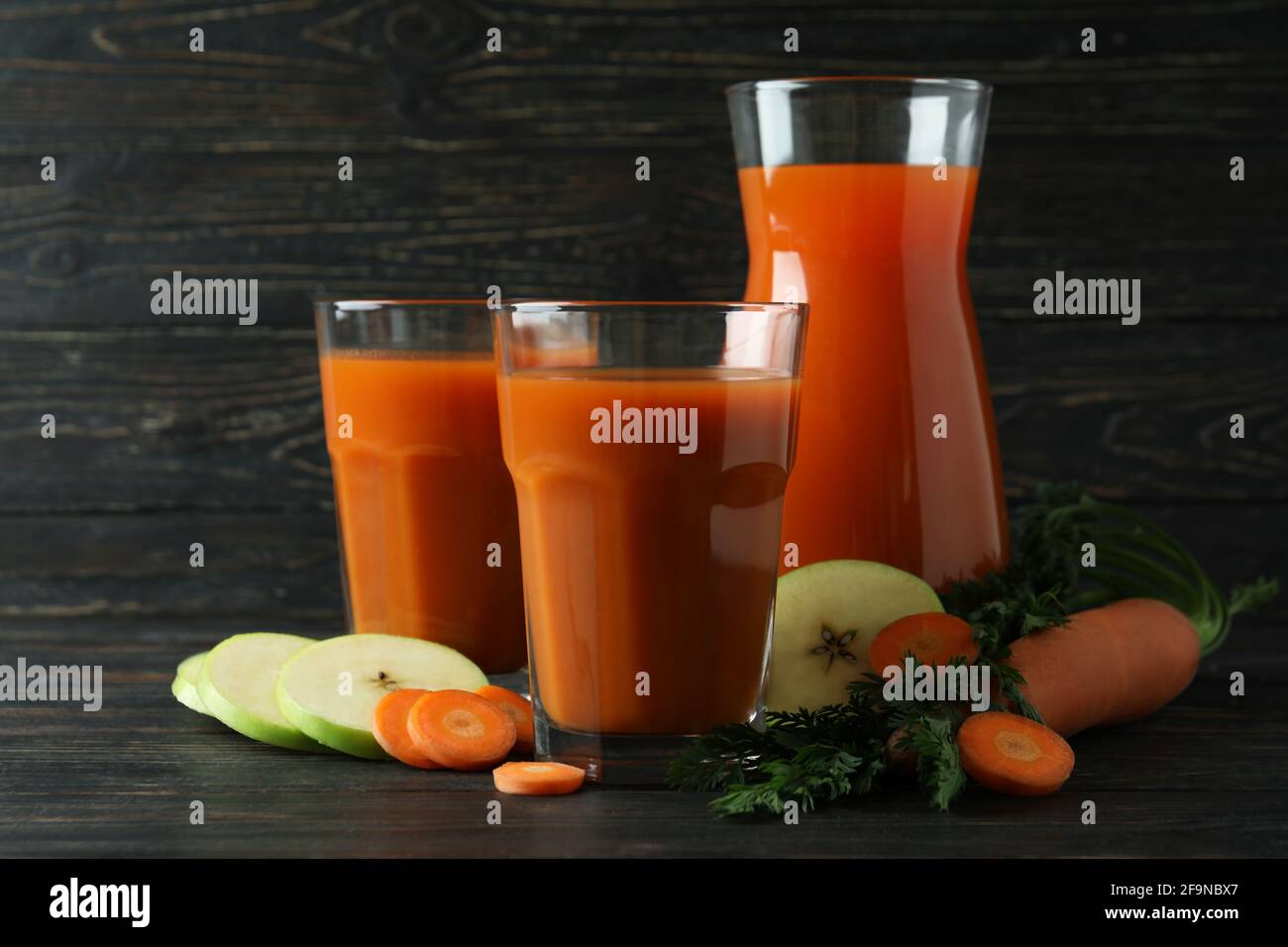 Bicchieri e caraffa con succo e ingredienti su sfondo di legno Foto Stock