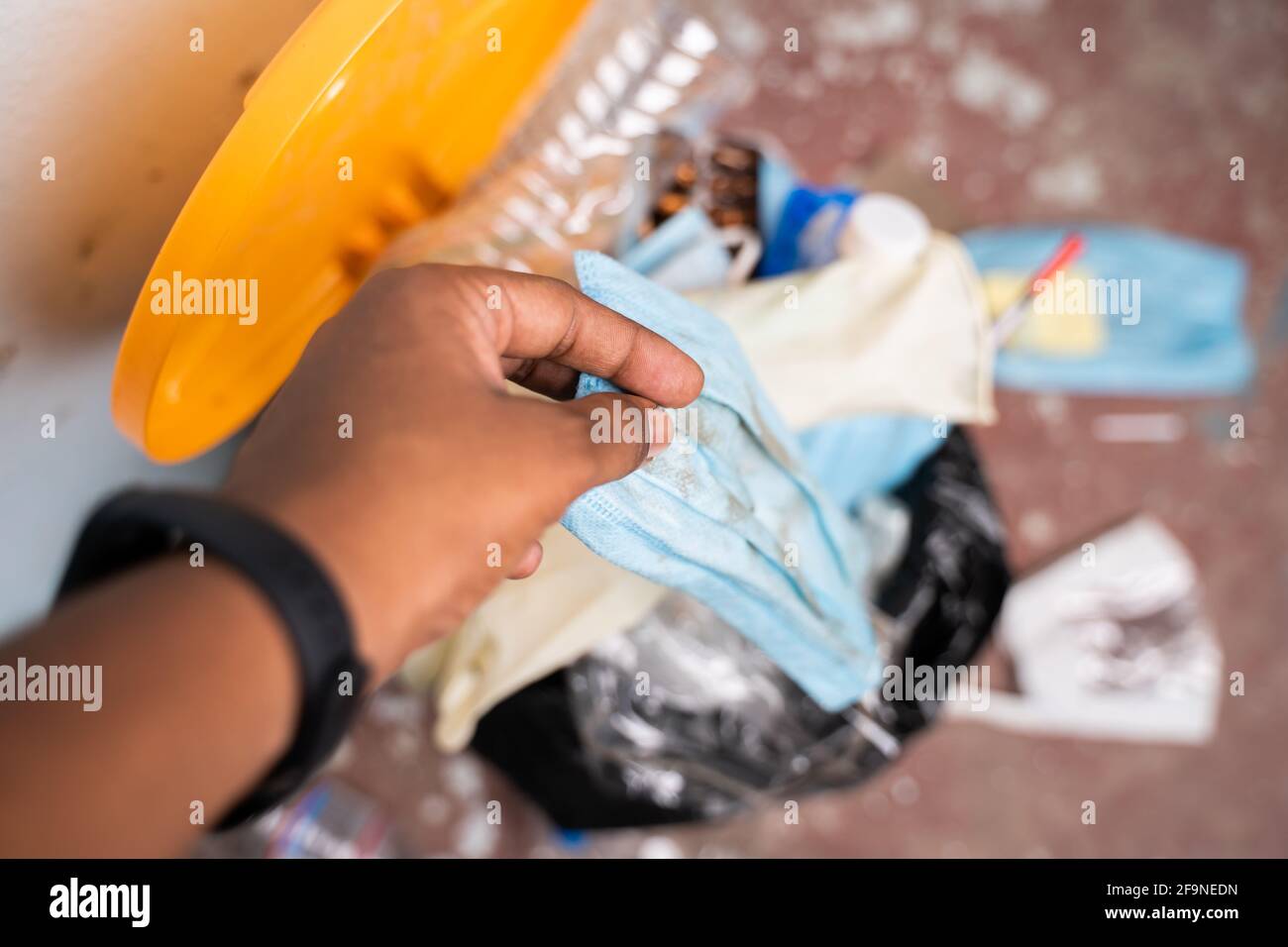 Shot POV di assistenza sanitaria o mani del medico che lanciano un solo uso maschera medica monouso e guanti in cestino pieno di rifiuti o bidone della spazzatura all'ospedale Foto Stock
