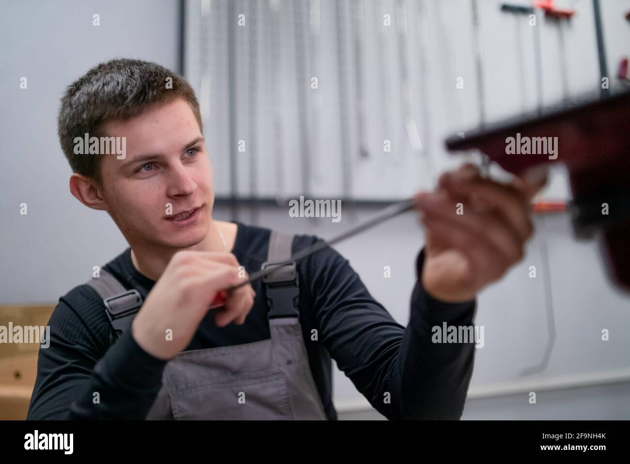 Ritratto di giovane specialista concentrato di rimozione ammaccature su riparazione auto stazione Foto Stock