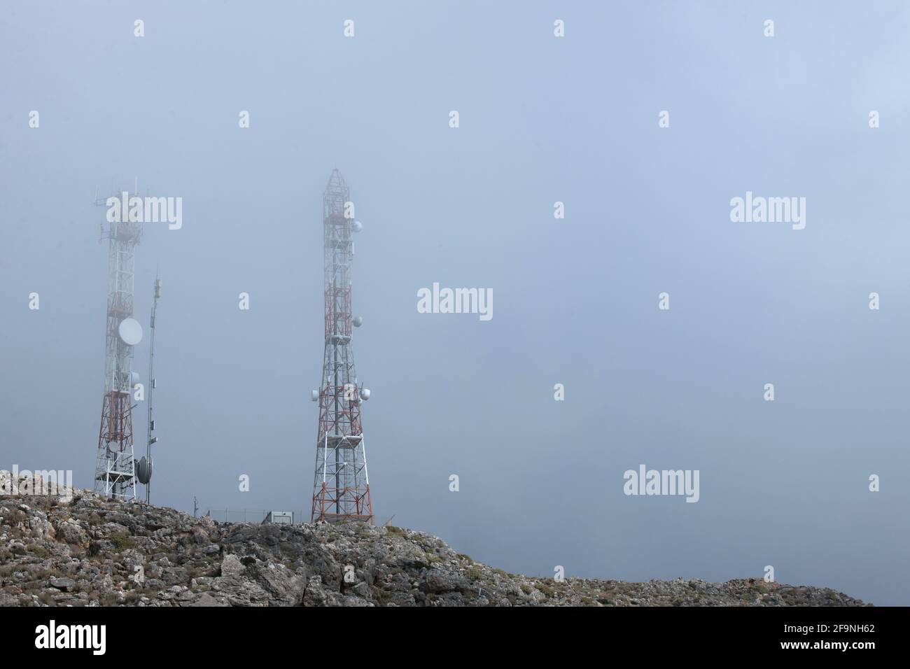 Vista dal suolo delle torri di telecomunicazione nelle nuvole su una vetta di montagna sull'isola di Creta. Foto Stock