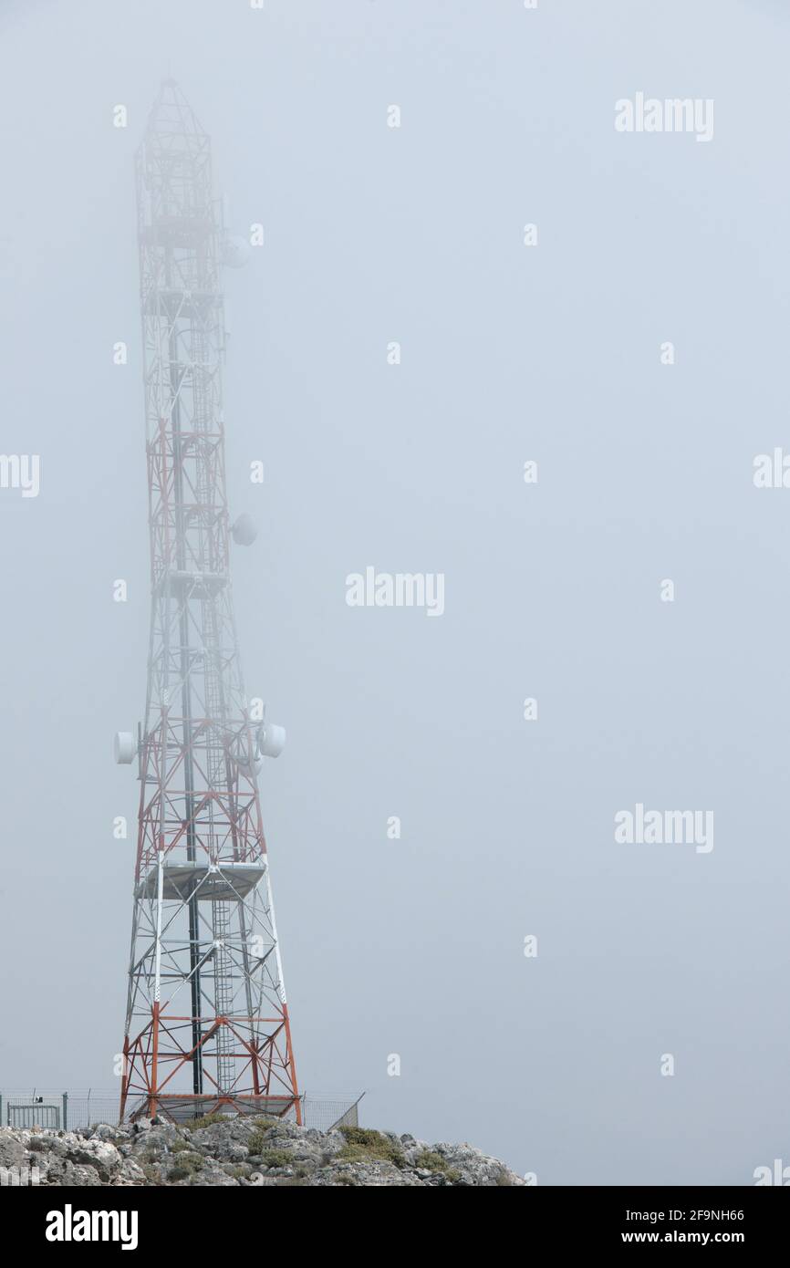 Vista dal suolo delle torri di telecomunicazione nelle nuvole su una vetta di montagna sull'isola di Creta. Foto Stock