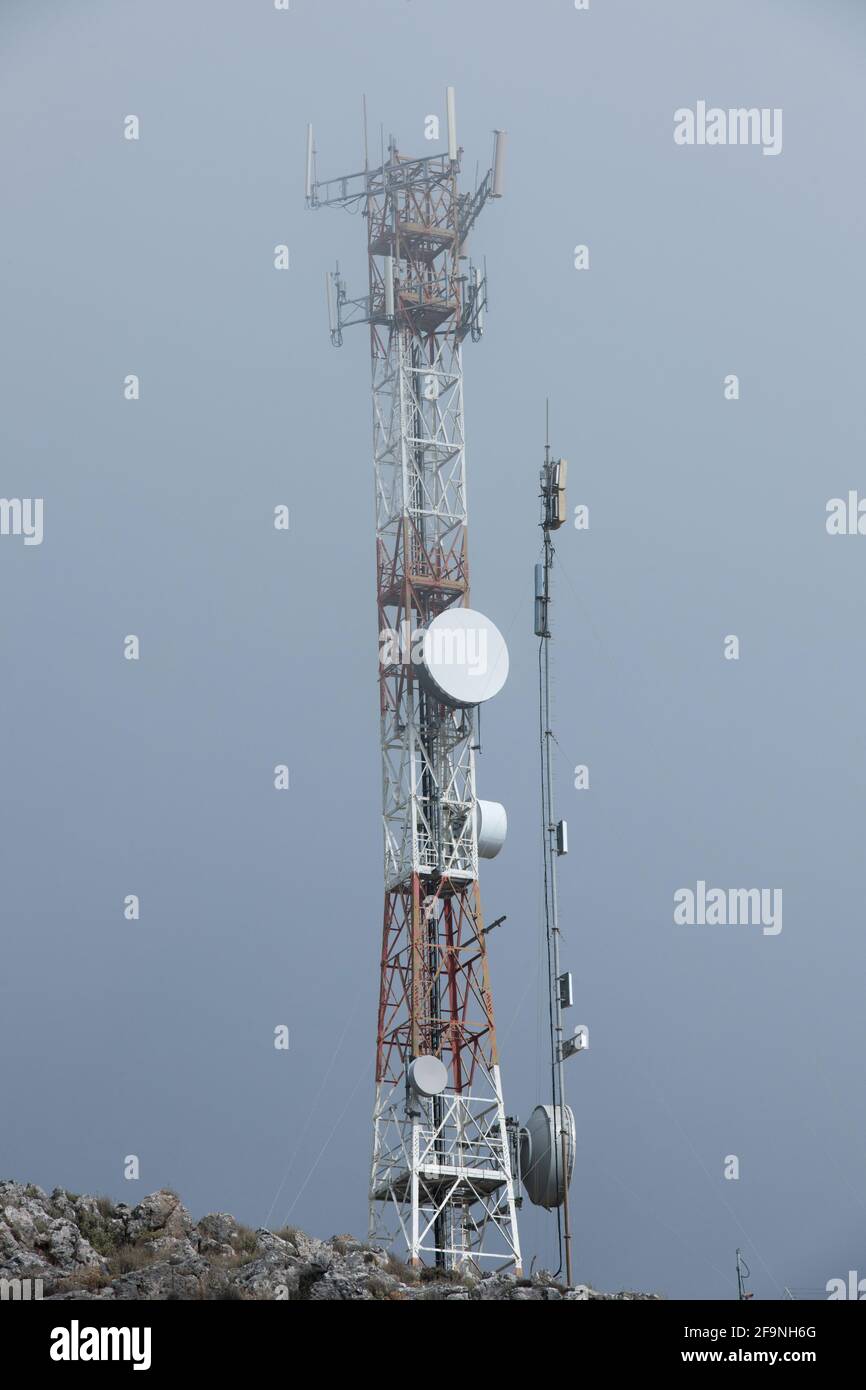 Vista dal suolo delle torri di telecomunicazione nelle nuvole su una vetta di montagna sull'isola di Creta. Foto Stock