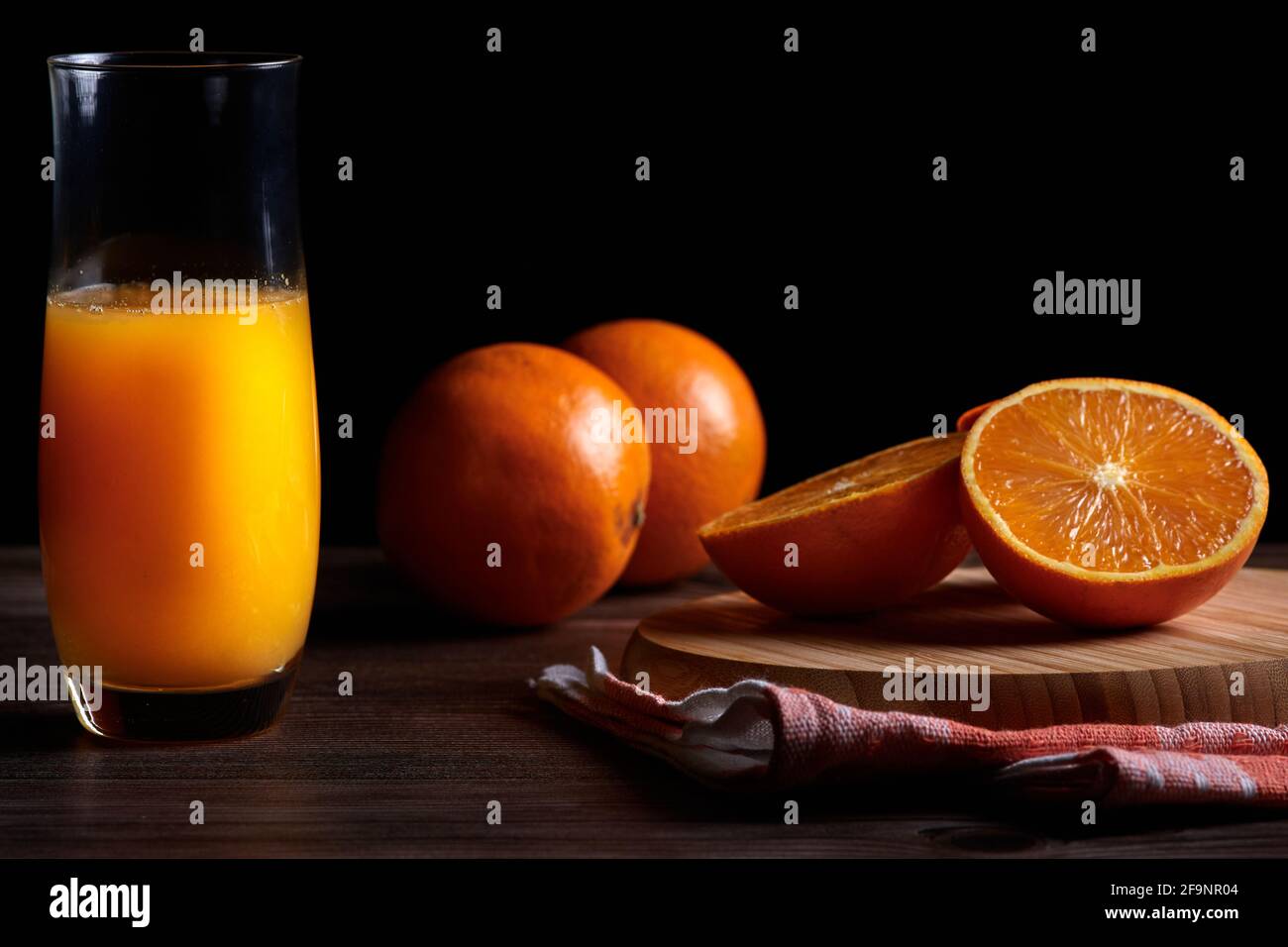 Vasetto in vetro di succo d'arancia fresco appena spremuto con frutta fresca su tavolo di legno. Spazio copia e sfondo nero Foto Stock