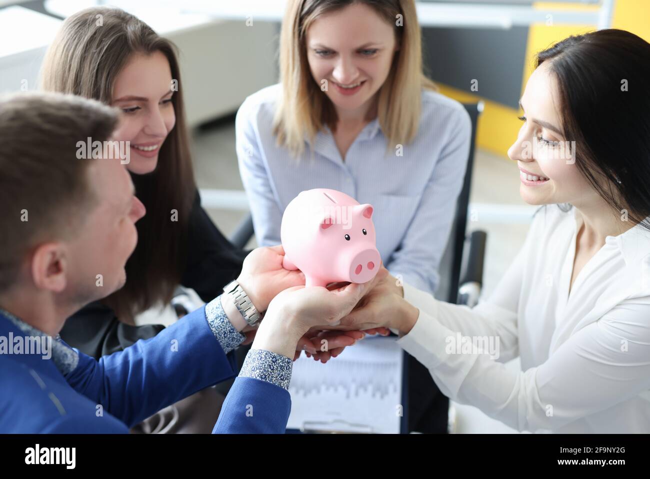 Gruppo di persone di successo affari che tengono rosa piggy banca in le loro mani in primo piano Foto Stock