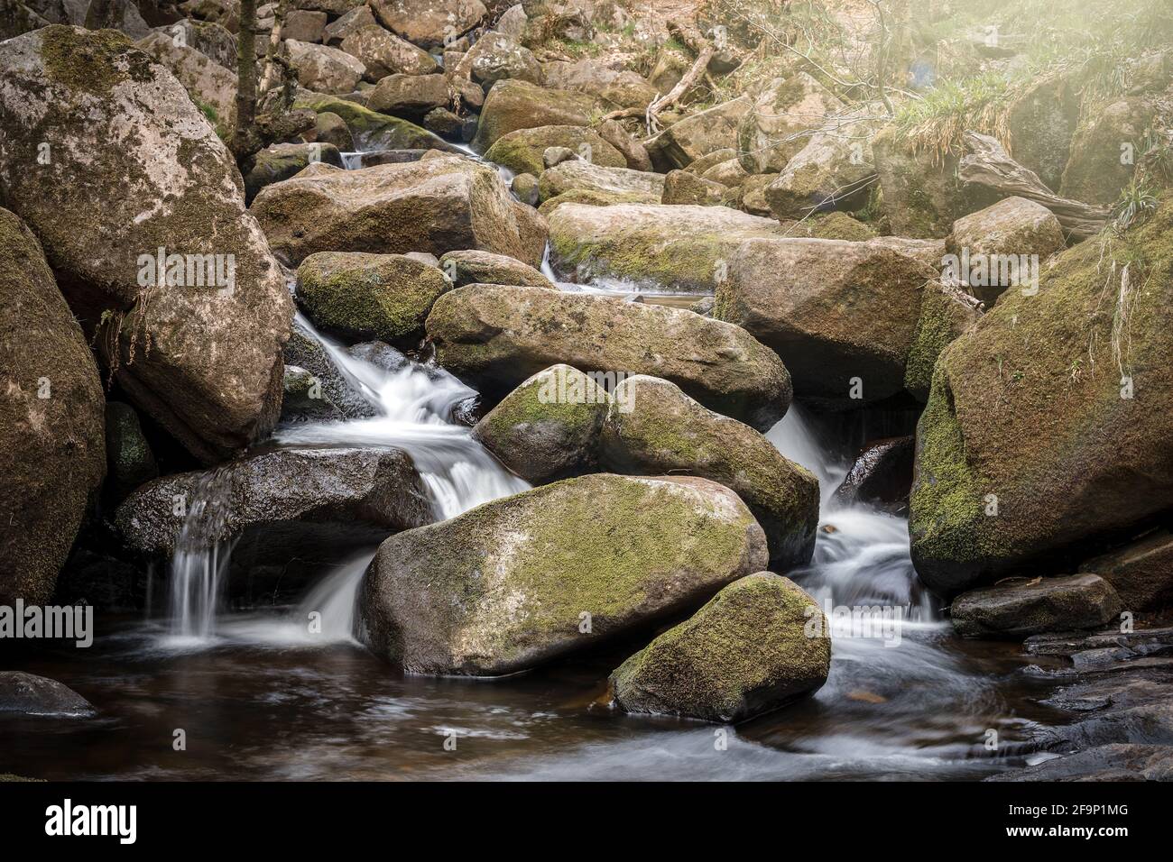 Ruscello che scorre attraverso la cascata rocciosa. Longe esposizione movimento sfocatura tranquilla Peak District all'aperto pietre del fiume. Foto Stock