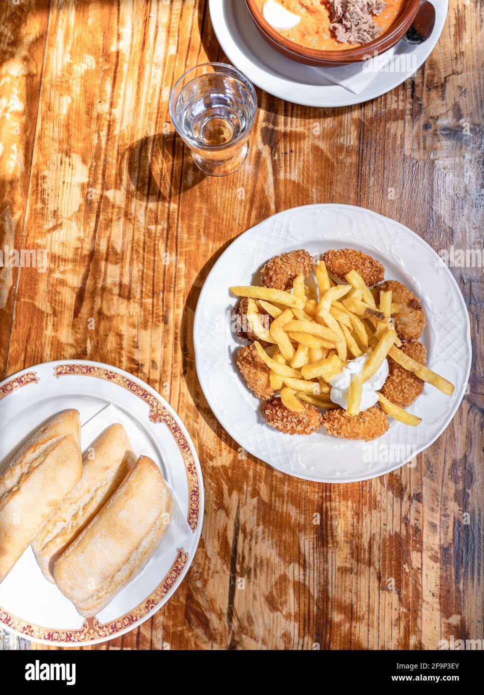 Piatto di cibo spagnolo fatto in casa in un tavolo di legno. Un piatto con crocchette con patate fritte e salsa di alioli. Foto Stock
