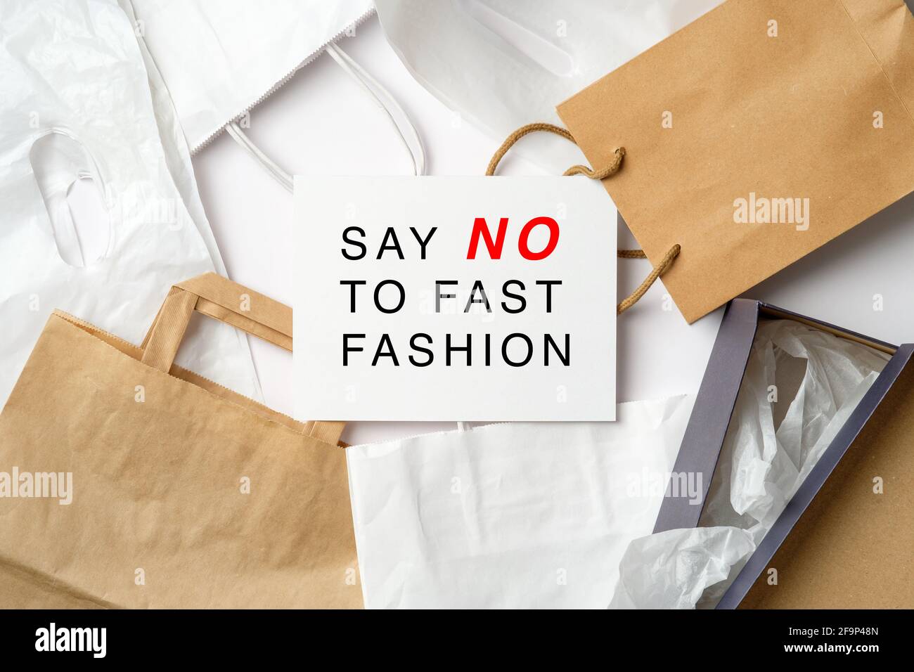 Dire No a Fast Fashion segno su carta carta su un mucchio di borse della spesa. Fast Fashion è male per l'ambiente Foto Stock