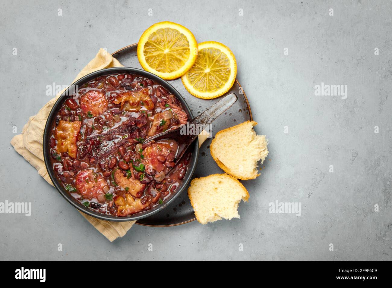 Feijoada in nero ciotola grigio tavolo. Cucina brasiliana e portoghese tradizionale fagioli stufato di carne Foto Stock