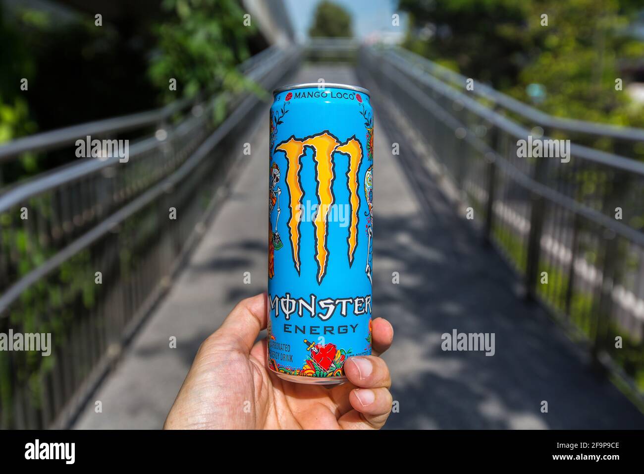 Una mano che regge il bellissimo design di una bevanda aromatizzata Monster Energy mango loco. Foto Stock