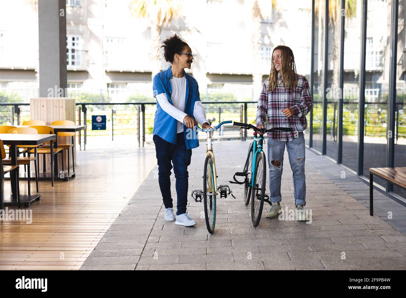 Due amici di razza maschile felici che si sfrecciare in bicicletta per strada e parlare. Stile di vita urbano verde, fuori e circa in città. Foto Stock
