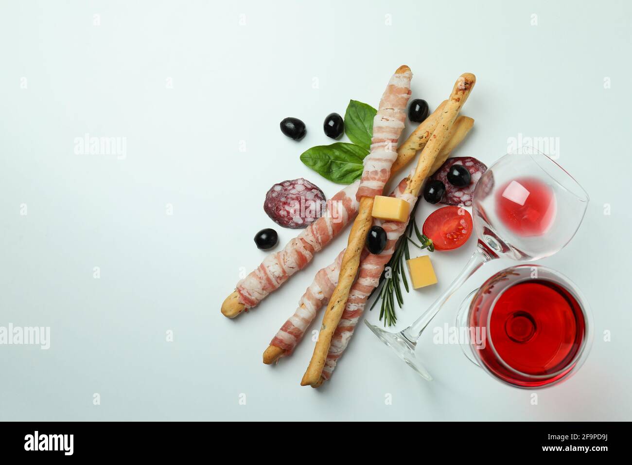 Grissini con pancetta, spuntini e vino su sfondo bianco Foto Stock