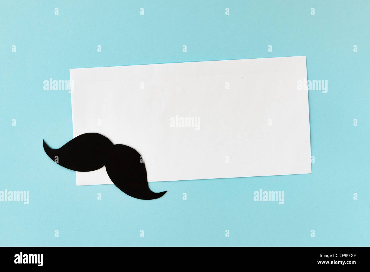 buon giorno del padre, composizione di baffi neri e busta su sfondo blu, biglietto di auguri con foglio bianco di carta e posto per il testo Foto Stock