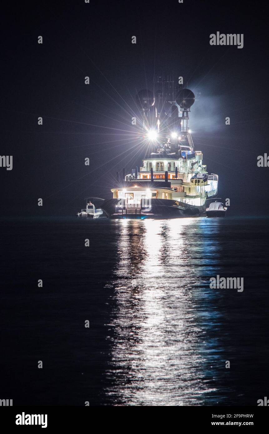 vista notturna della nave da pesca illuminata che si riflette sull'acqua nella baia di napoli in italia. Foto Stock