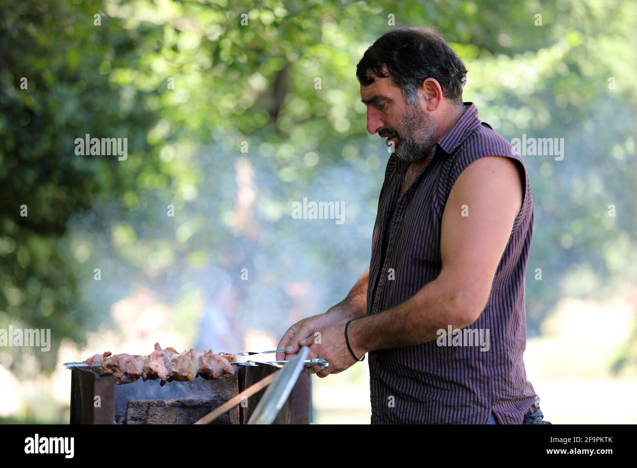 17.07.2018, Keda, Ajaria, Georgia - uomo che grigliano i kebab di carne su una griglia di carbone in un parco. 00S180717D563CAROEX.JPG [VERSIONE DEL MODELLO: NO, RELEDA PROPRIETÀ Foto Stock