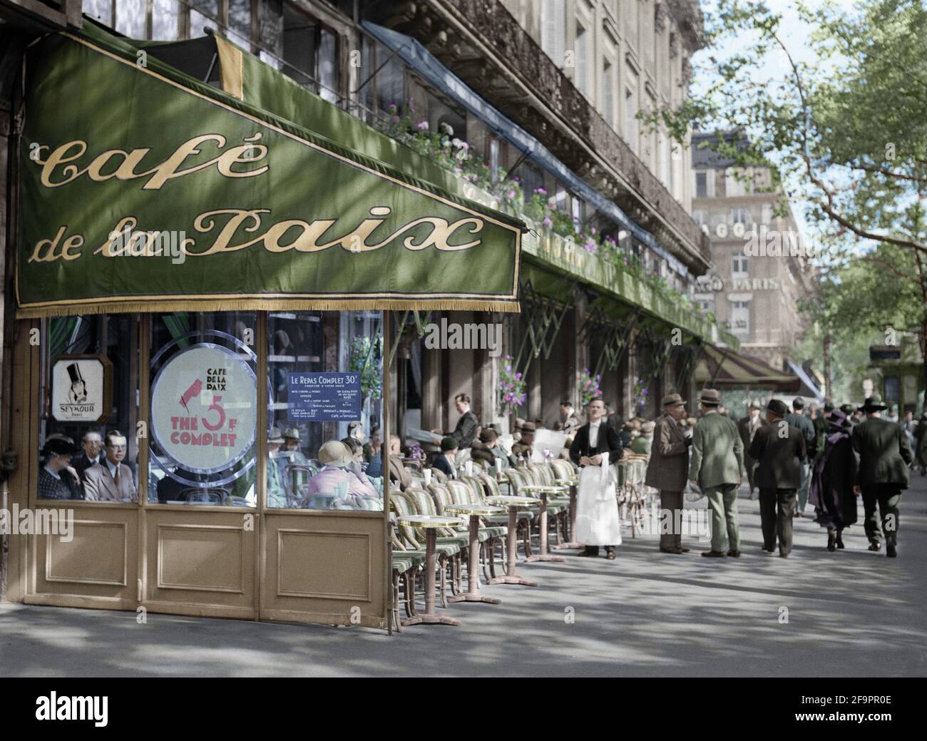 Café de la Paix situato in Boulevard des Capucines nel 1935. PARIGI, FRANCIA: Le fotografie COLORATE portano PARIGI? lunga e vibrante storia alla vita. Uno Foto Stock