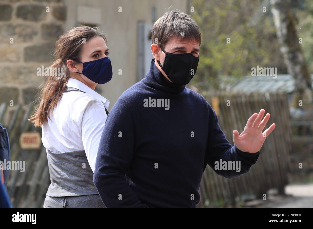 L'attore Tom Cruise ondeggia agli onlookers mentre cammina verso il set del suo ultimo progetto, che sta filmando ai sidi della stazione ferroviaria nel villaggio di Levisham nei Moors di North York. Data immagine: Martedì 20 aprile 2021. Foto Stock