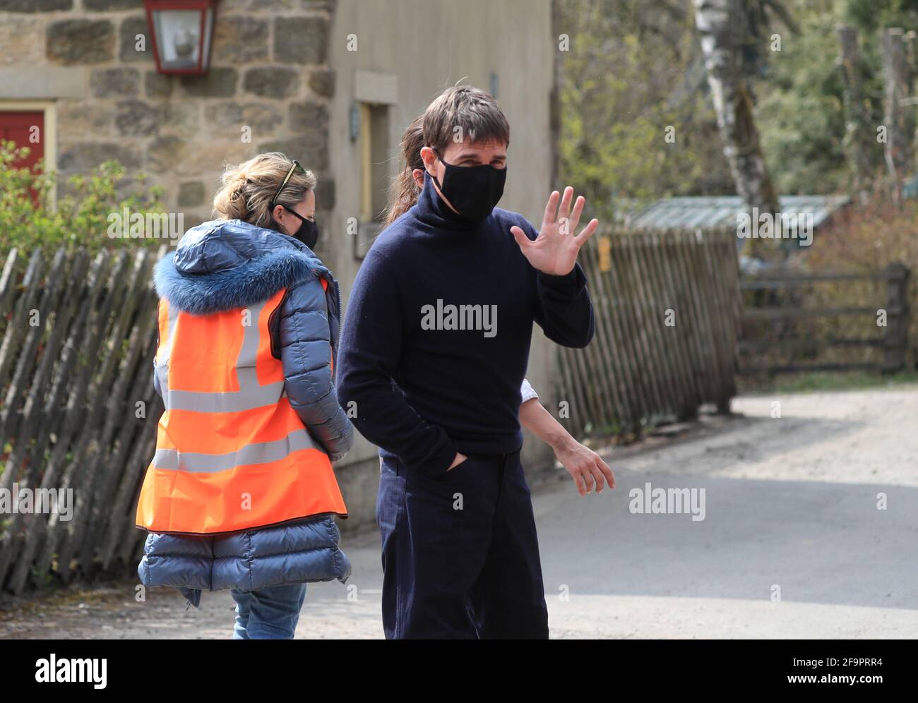 L'attore Tom Cruise ondeggia agli onlookers mentre cammina verso il set del suo ultimo progetto, che sta filmando ai sidi della stazione ferroviaria nel villaggio di Levisham nei Moors di North York. Data immagine: Martedì 20 aprile 2021. Foto Stock