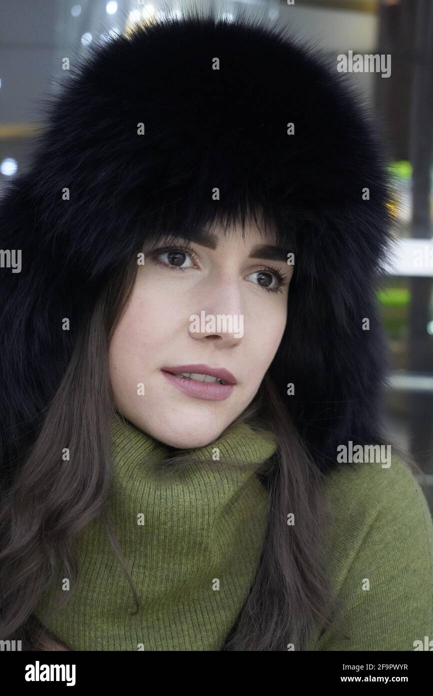 Ritratto di donna casual stile in pelliccia d'inverno cappello primo piano, viso e mani su sfondo scintillante Foto Stock