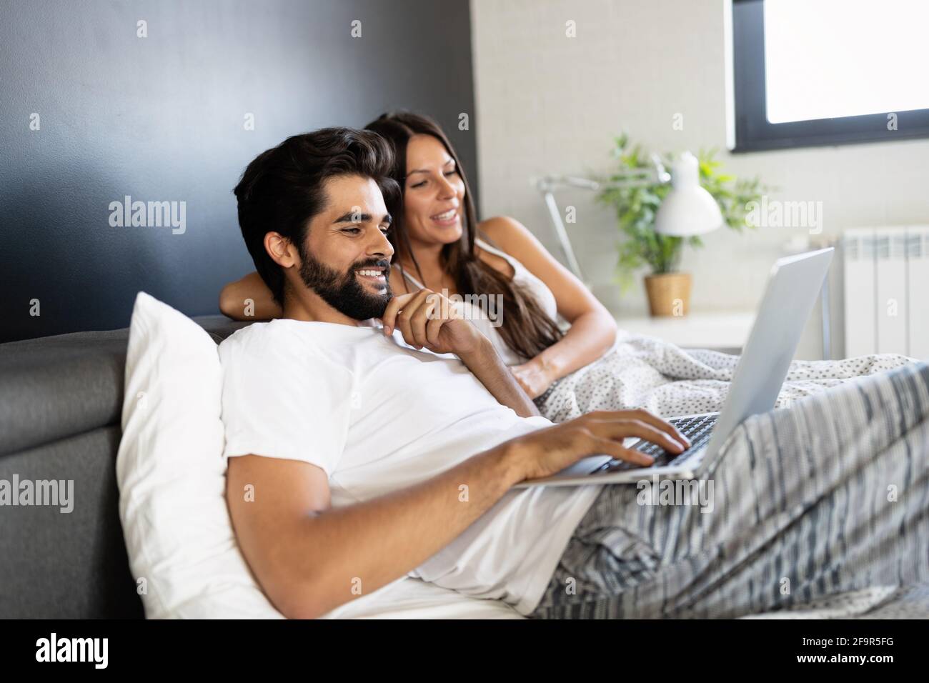 Giovane felice sorridente coppia con notebook in camera da letto Foto Stock