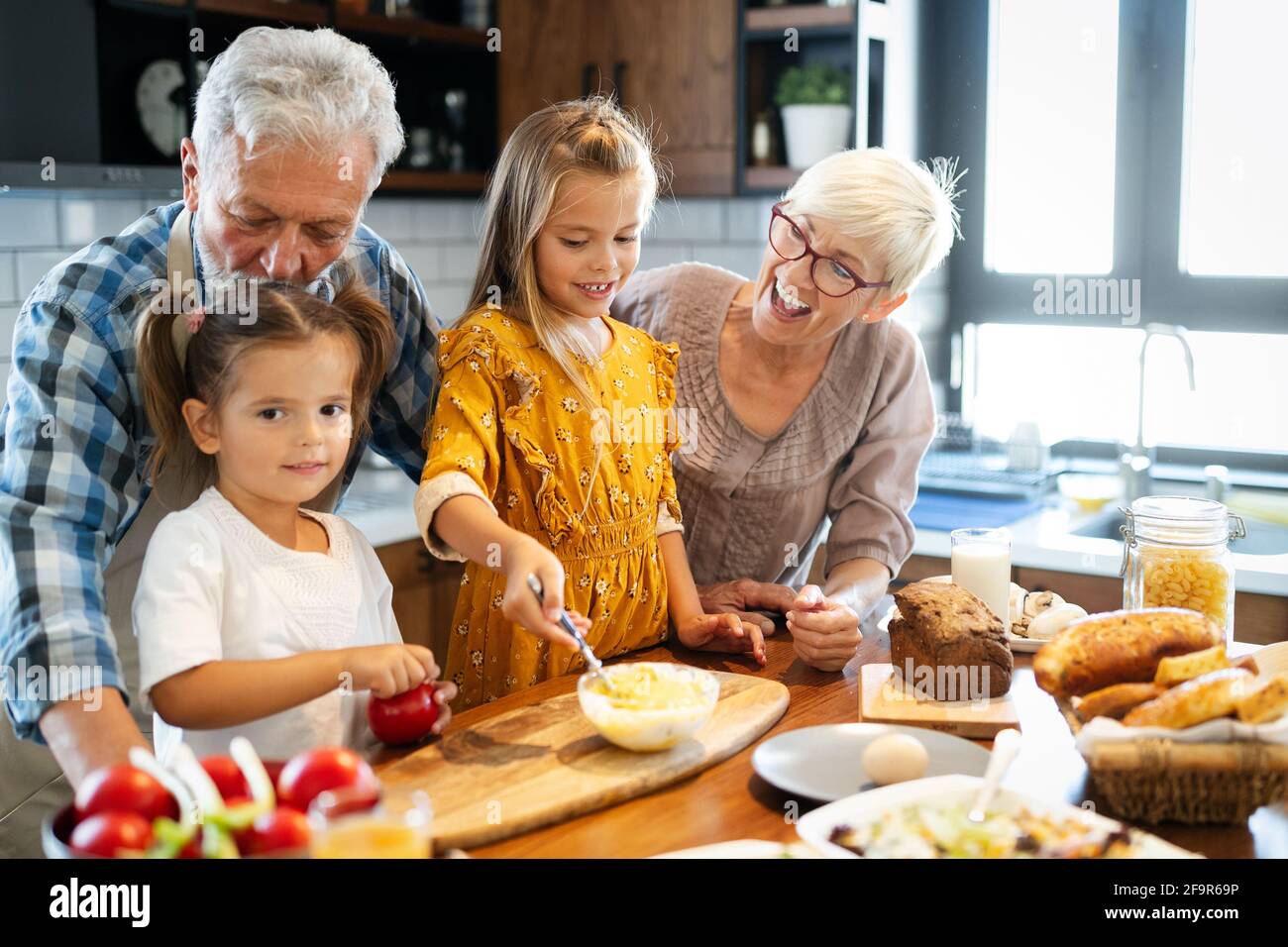 Felice grandchildrens ragazze avente la colazione con i suoi nonni Foto Stock