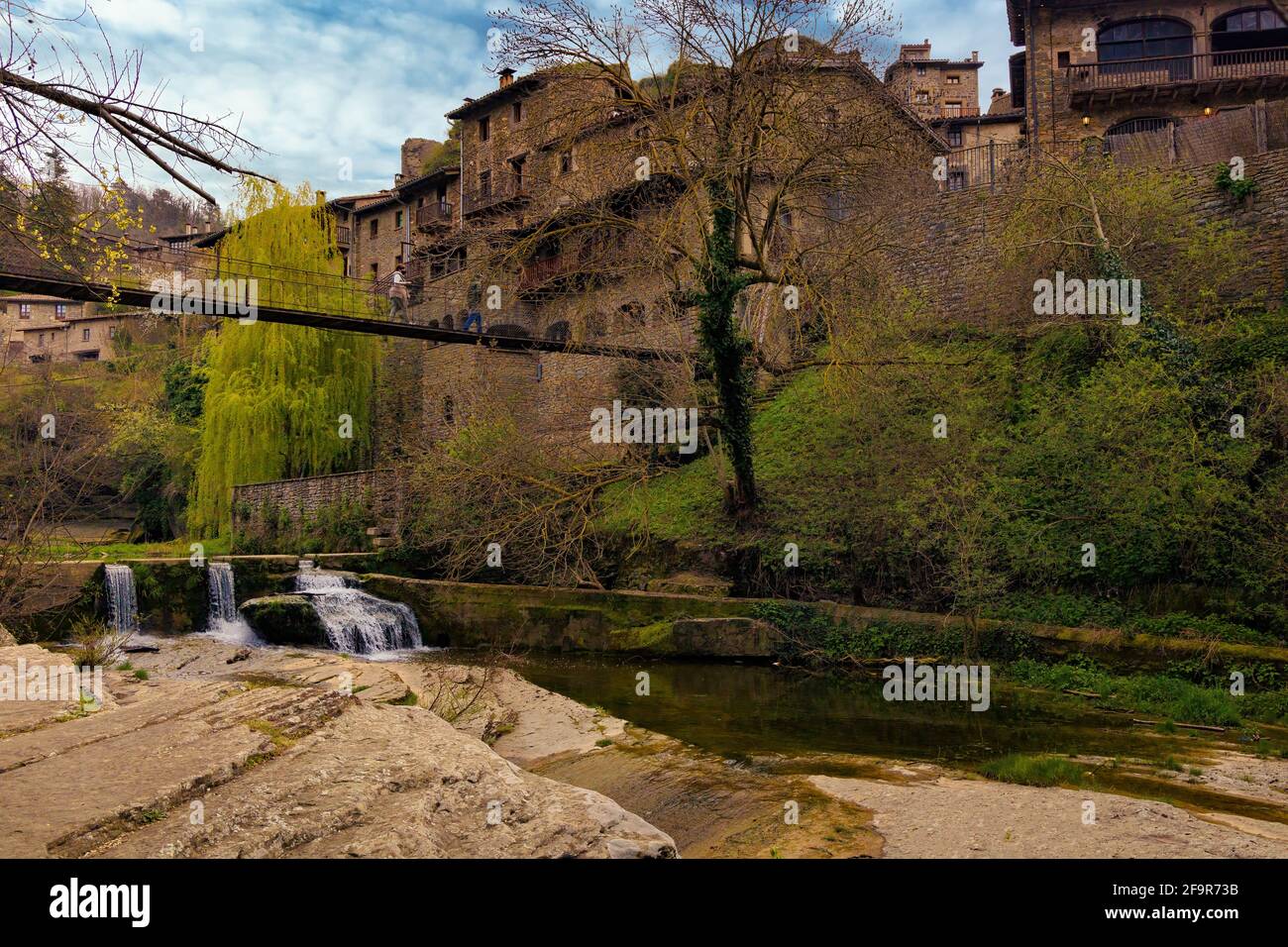 Vista della passerella aerea che attraversa il torrente e le cascate fino al centro del centro storico della città di Rupit. Catalogna, Spagna Foto Stock