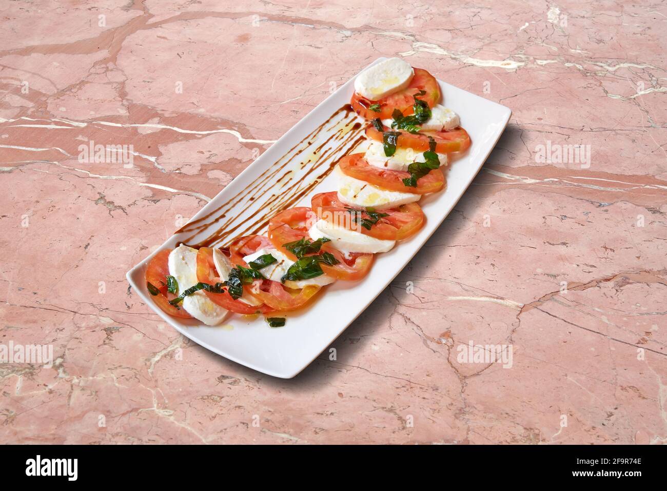 Cibo da pub. Piatto di pomodori mozzarella su marmo rosa Foto Stock