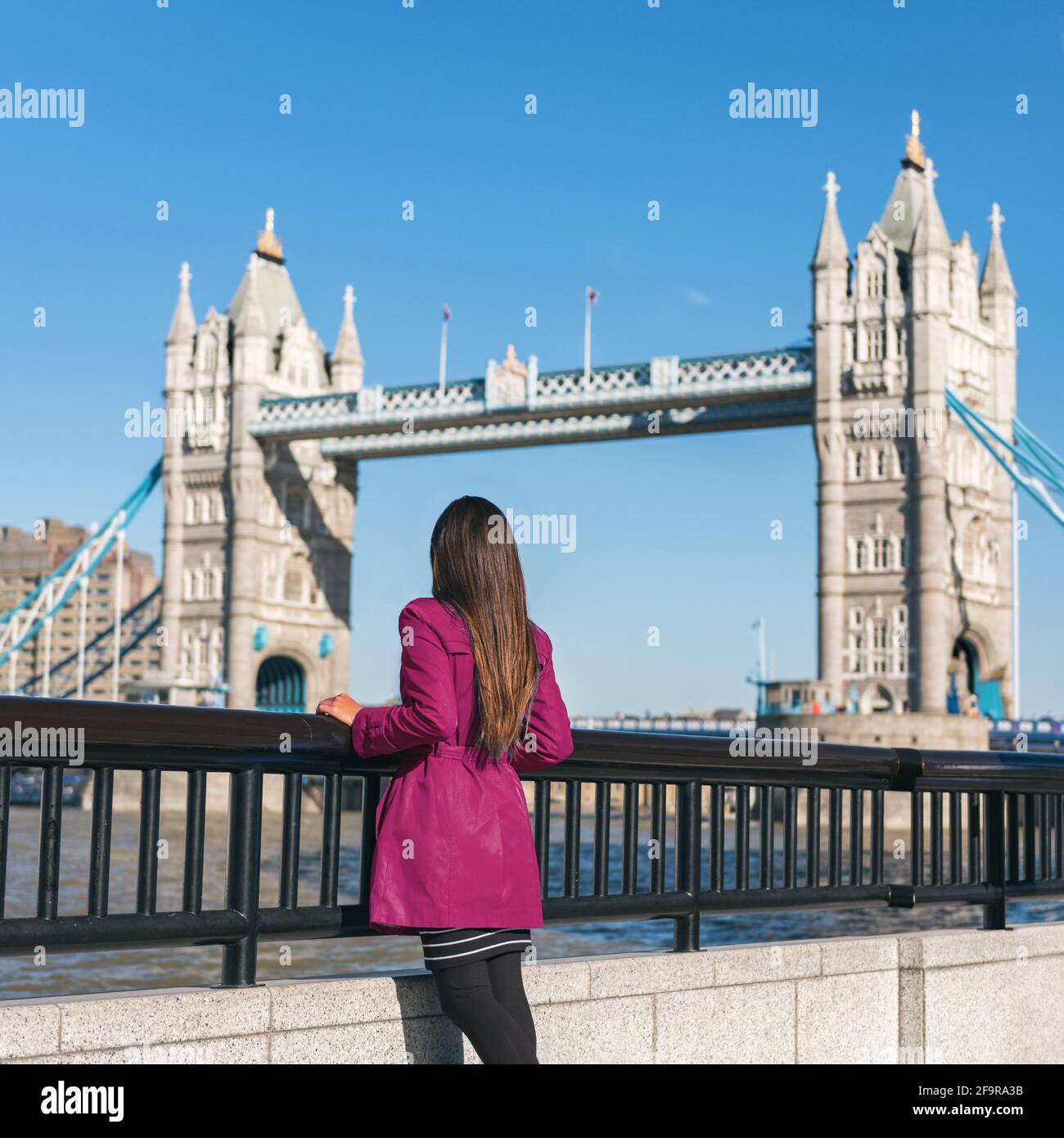 La gente di Londra la donna turistica della città che guarda la vista del Ponte della Torre in un cappotto di trincea rosso. Ponte. Elegante donna moda ragazza che cammina Foto Stock