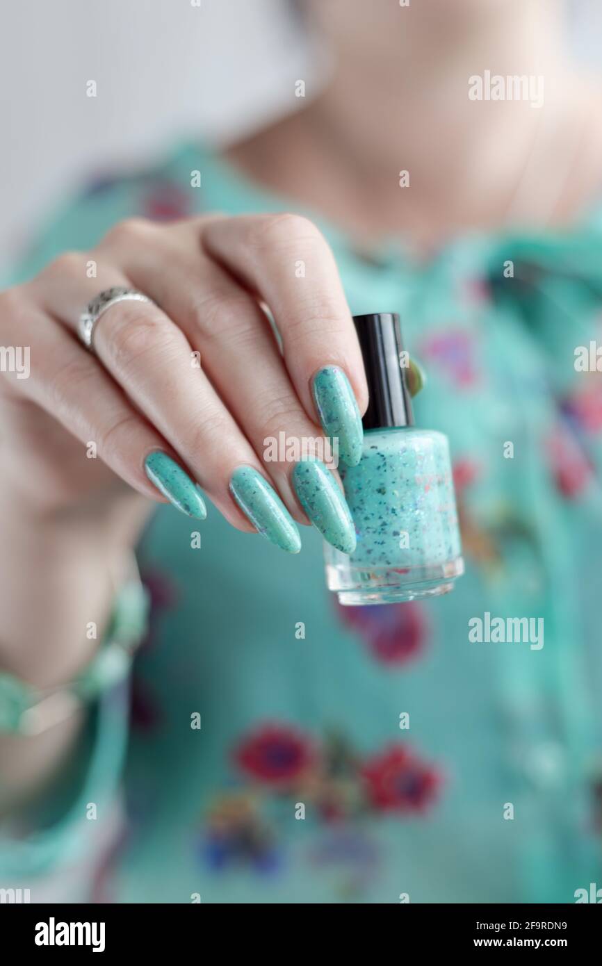 Mano femminile con unghie lunghe e manicure blu turchese con bottiglie di  smalto per unghie Foto stock - Alamy