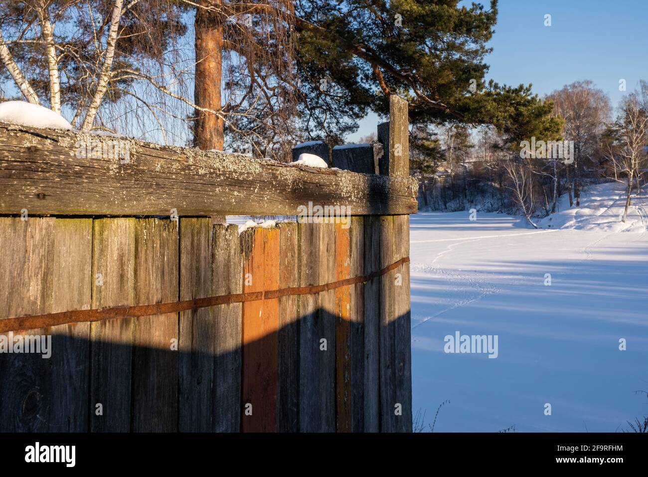 L'angolo di una vecchia recinzione in legno alla luce del sole invernale, la Russia. Foto Stock