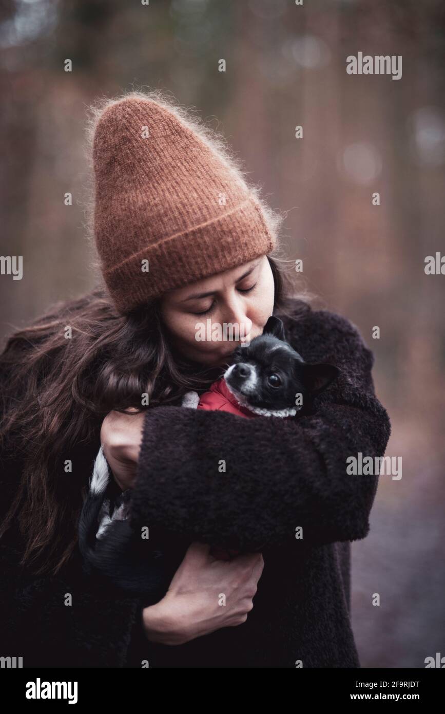 giovane donna con cappelli caldi e bacia chihuahua minuscola cane Foto Stock