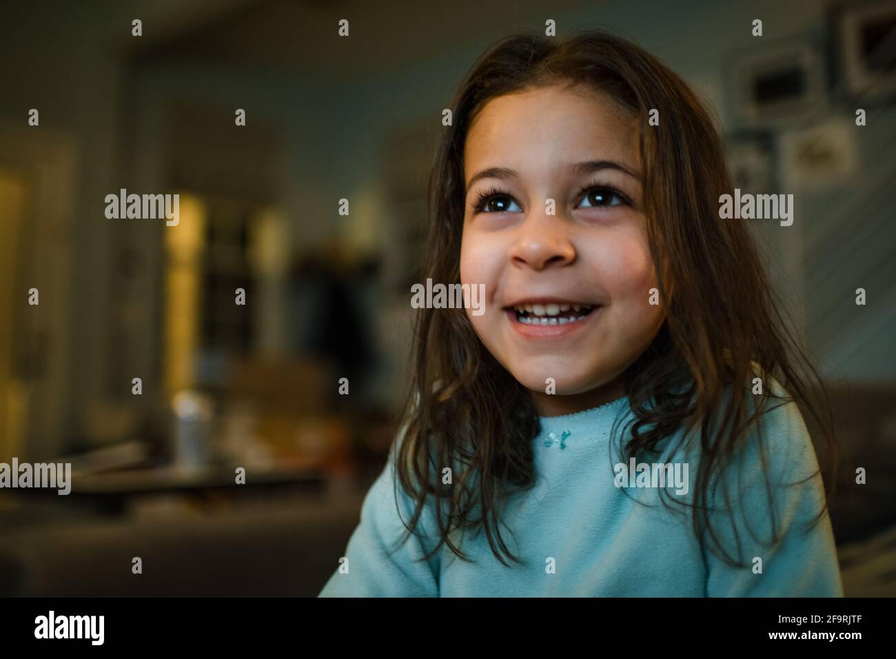 Ragazza di 4 anni che guarda la tv la sera, grande sorriso Foto Stock