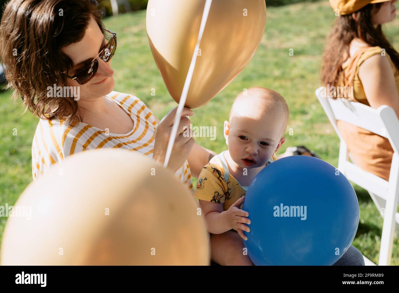 Mamma e bambino giocano con palloncini alla cerimonia di laurea covid Foto Stock