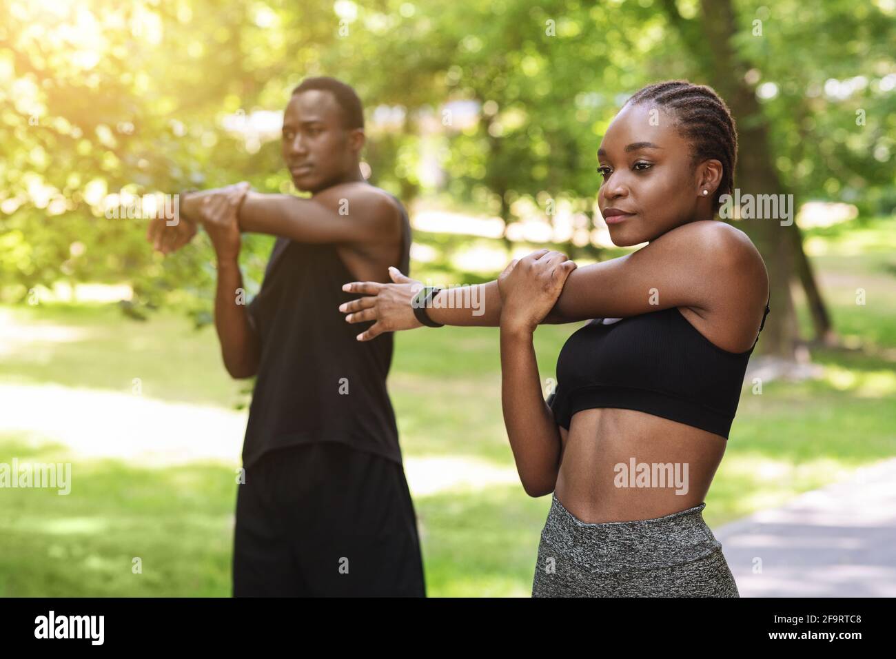 Coppia africana motivata che si scalda prima di correre a Park, allenarsi insieme all'aria aperta Foto Stock