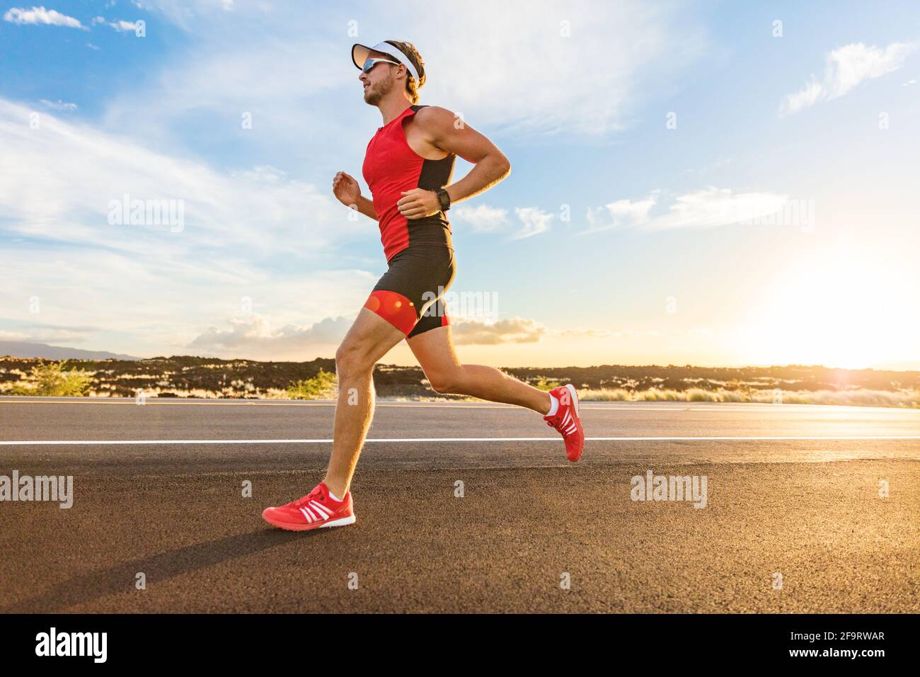Triathlon - triatleta uomo che corre in tuta triathlon allenamento per gara  di ironman. Corridore maschile che si esercita sulla Big Island Hawaii.  Tramonto Foto stock - Alamy