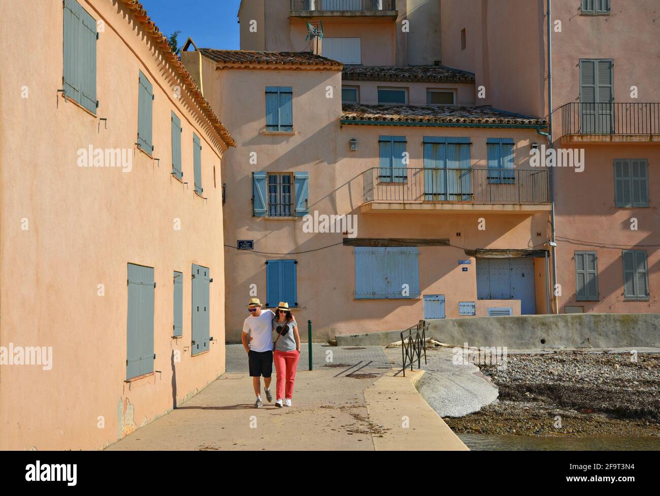 Giovane coppia a piedi lungo la spiaggia la Ponche con pittoresche case Provençal sullo sfondo a Saint-Tropez, Costa Azzurra Francia. Foto Stock
