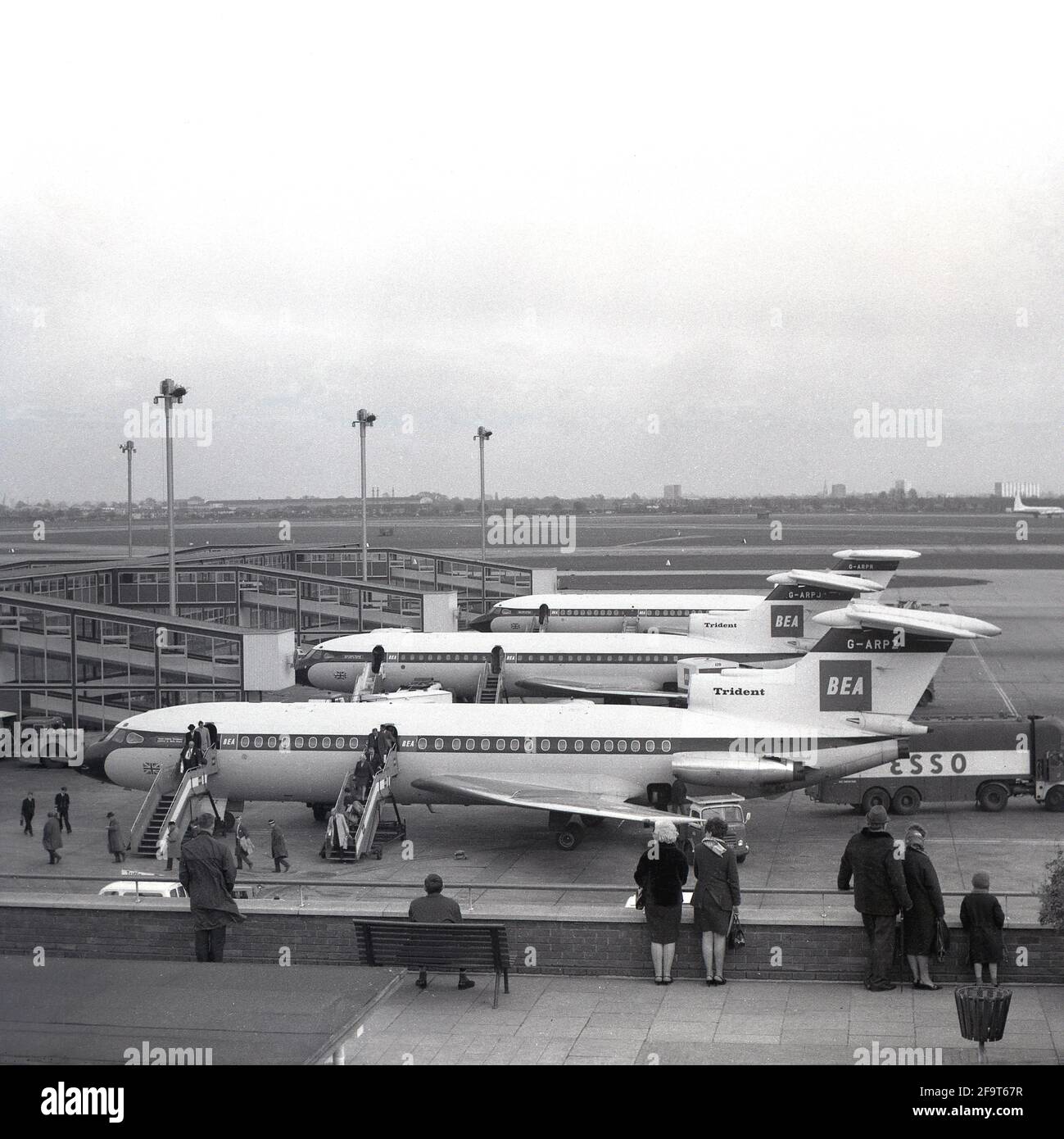 1967, storico, all'aeroporto di heathrow, tre aerei BEA Hawker SiddeleyTrident a reazione parcheggiati fuori dai cancelli d'imbarco del terminal Europa, con i passeggeri che sbarcano da uno degli aerei, Londra, Inghilterra, Regno Unito. Un anno prima del 1966, l'aeroporto di Londra è stato rinominato Heathrow dopo l'originario villaggio rurale di Heath Row che ha fornito la terra per l'aeroporto. Il tetto dell'Europa Terminal era una popolare piattaforma di osservazione per i visitatori di vedere gli aerei e l'area circostante. Foto Stock