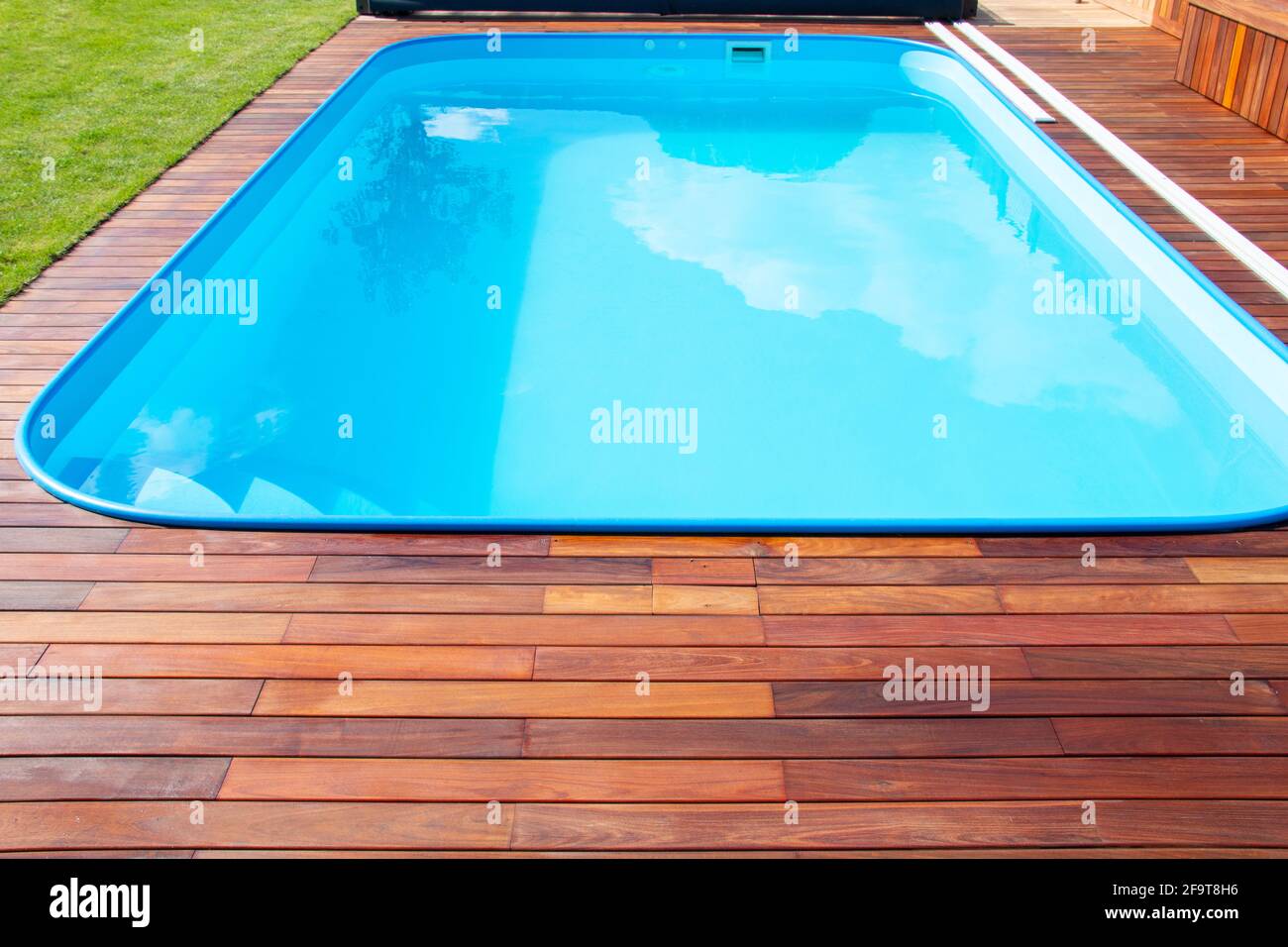 Piscina con terrazza in legno di Ipe e erba verde. Legno esotico Ipe terrazza accanto piscina primo piano Foto Stock