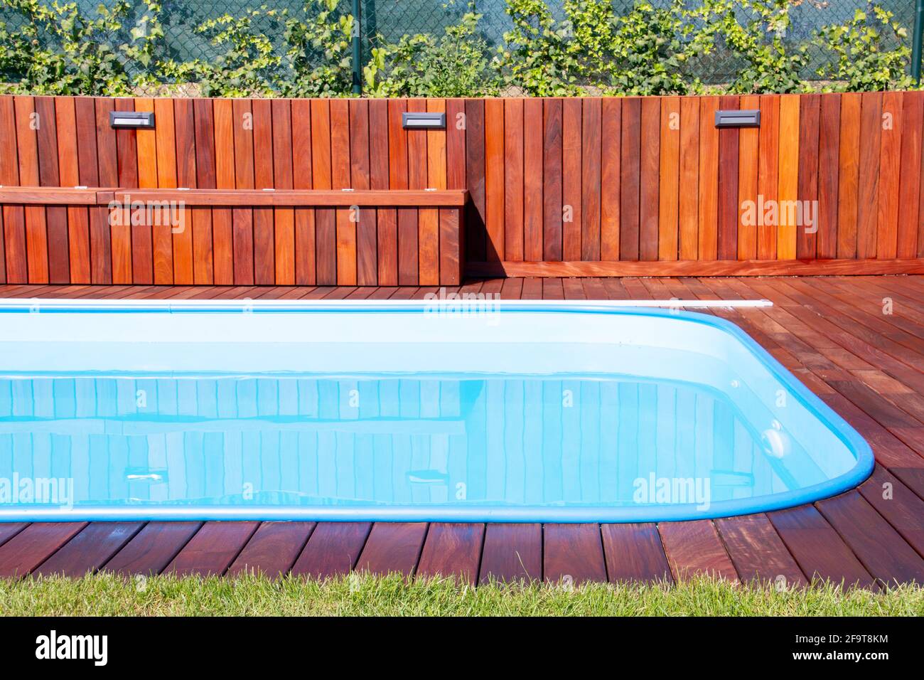 Piscina con terrazza in legno di Ipe e erba verde. Legno esotico Ipe terrazza accanto piscina primo piano Foto Stock