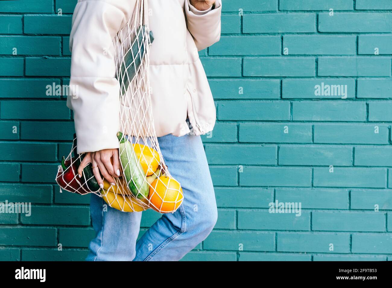 Concetto di zero sprechi. Primo piano donna che tiene riutilizzabile borsa della spesa in rete con frutta e verdura. Primo piano su eco-friendly mesh shopper. Foto Stock