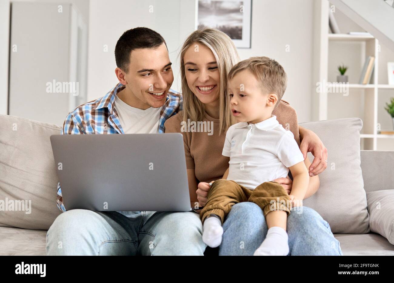 Figlio di capretto che impara il computer che fa lo shopping in linea seduto con i genitori sul divano. Foto Stock