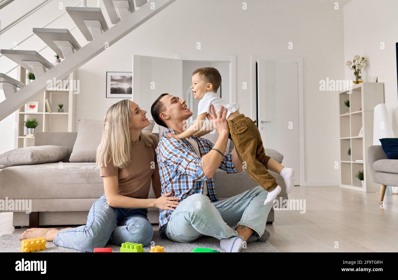 Allegra coppia di famiglia che gioca con il ragazzo felice in soggiorno moderno. Foto Stock